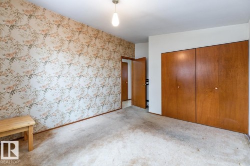 Room featuring a patterned wallpaper accent wall, light-colored carpeting, and a ceiling-mounted light fixture - 13437 118 Street, Edmonton, AB - Indoor Photo Showing Other Room