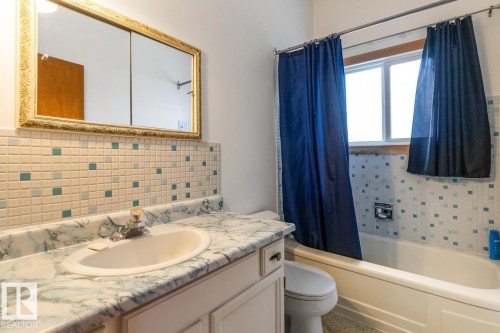 Bathroom vanity with an integrated sink, faux marble countertop, and white cabinetry - 13437 118 Street, Edmonton, AB - Indoor Photo Showing Bathroom