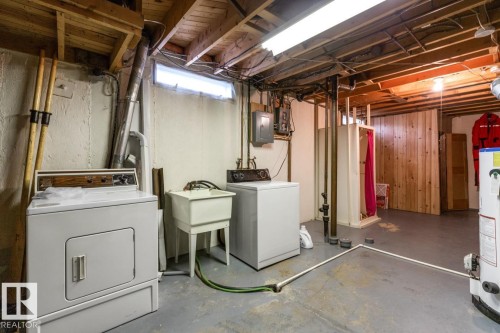 Utility area featuring a laundry sink, exposed wood ceiling joists, concrete flooring, and a water heater - 13437 118 Street, Edmonton, AB - Indoor Photo Showing Laundry Room
