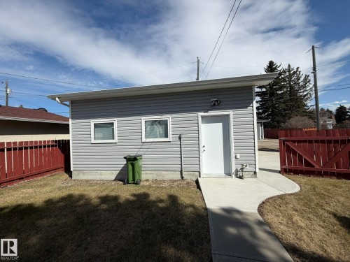 Detached auxiliary structure featuring horizontal siding, two windows, and a single-entry door with an external light fixture - 13437 118 Street, Edmonton, AB - Outdoor With Exterior