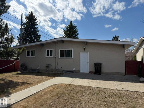 Stucco exterior featuring multiple windows and a white entrance door - 13437 118 Street, Edmonton, AB - Outdoor