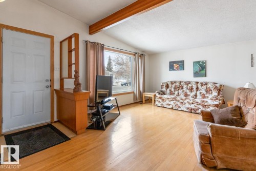 Living room featuring wood-finish flooring and a vaulted ceiling with exposed wood beams - 13437 118 Street, Edmonton, AB - Indoor Photo Showing Living Room