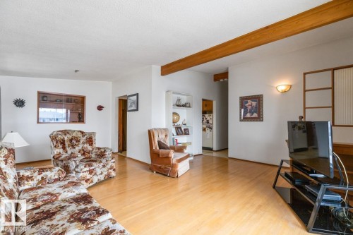 Spacious living area featuring wood-finish flooring, exposed ceiling beams and a built-in wall display cabinet - 13437 118 Street, Edmonton, AB - Indoor Photo Showing Living Room