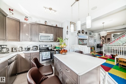 The kitchen features stainless steel appliances, a white subway tile backsplash, and an island with seating - 8204 224 Nw, Edmonton, AB - Indoor Photo Showing Kitchen