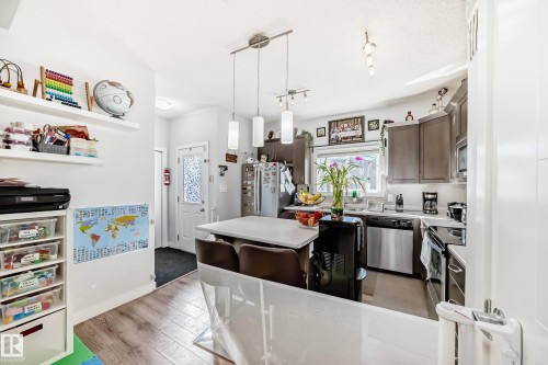 The kitchen features stainless steel appliances, dark cabinetry, and an island with seating - 8204 224 Nw, Edmonton, AB - Indoor Photo Showing Kitchen With Upgraded Kitchen