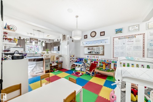 The property features an open-concept living space with white walls, recessed lighting, and a kitchen area with dark cabinetry, a window overlooking the sink, and a microwave oven - 8204 224 Nw, Edmonton, AB - Indoor Photo Showing Other Room