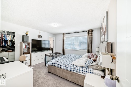 This inviting space features light gray carpeting, a built-in closet system, and a window with blinds and drapes - 8204 224 Nw, Edmonton, AB - Indoor Photo Showing Bedroom