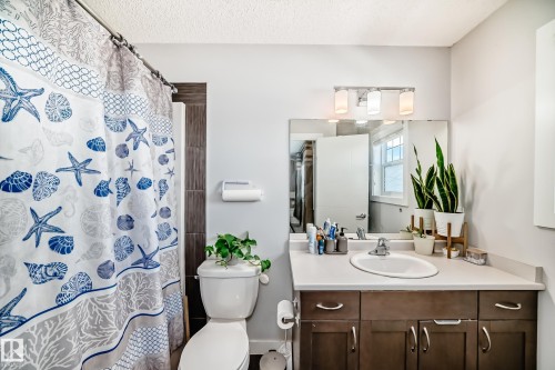 The bathroom features a vanity with a white countertop and dark wood cabinetry, a mirror, and a toilet - 8204 224 Nw, Edmonton, AB - Indoor Photo Showing Bathroom