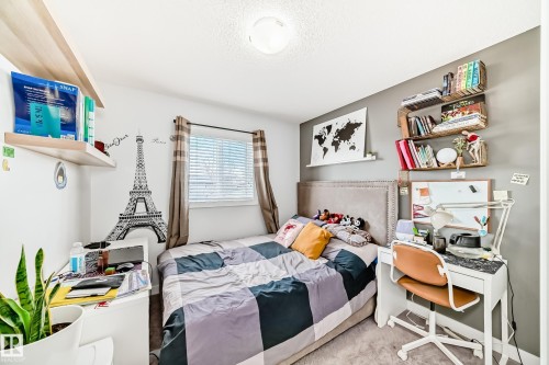 This room features a window with blinds and curtains, a bed with a studded headboard, and a desk with a task chair - 8204 224 Nw, Edmonton, AB - Indoor Photo Showing Bedroom