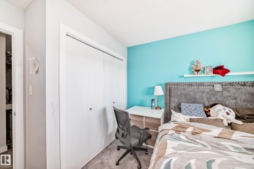 This room features a bright accent wall, a closet with sliding doors, and a built-in desk area - 8204 224 Nw, Edmonton, AB - Indoor