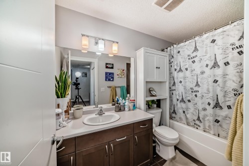 Bathroom featuring a vanity with a white countertop and dark wood cabinetry, a mirror with overhead lighting, a toilet, and a bathtub with a shower curtain - 8204 224 Nw, Edmonton, AB - Indoor Photo Showing Bathroom