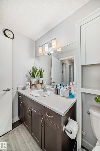 Bathroom featuring a vanity with a white countertop and a white sink, dark wood cabinetry, and a large mirror - 8204 224 Nw, Edmonton, AB - Indoor Photo Showing Bathroom