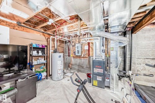 Utility area featuring a water heater, furnace, and exposed ceiling joists with visible ductwork - 8204 224 Nw, Edmonton, AB - Indoor Photo Showing Basement