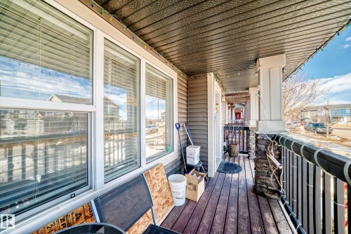 This property features a front porch with wood plank decking, a stone column, and a railing - 8204 224 Nw, Edmonton, AB - Outdoor With Deck Patio Veranda With Exterior