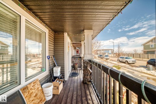 Inviting covered porch with a dark wood deck and stone column accents - 8204 224 Nw, Edmonton, AB - Outdoor With Exterior