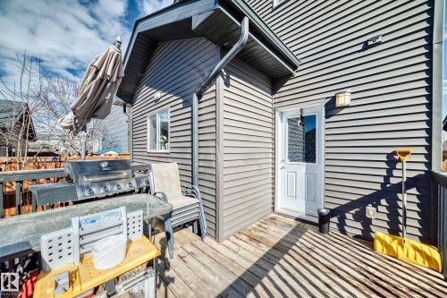 The property features a wooden deck with railing, gray exterior siding, and a white entrance door - 8204 224 Nw, Edmonton, AB - Outdoor
