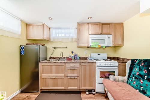 Kitchen with light wood finish cabinets, white appliances, light wood-style flooring, and recessed lighting - 3634 113 Avenue, Edmonton, AB - Indoor Photo Showing Kitchen With Double Sink