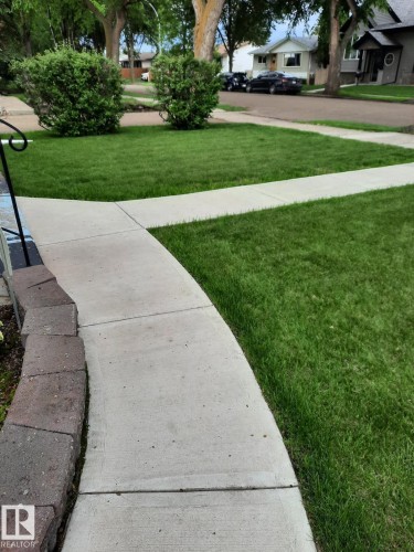 Manicured lawn with mature shrubs and trees, complemented by a concrete pathway - 3634 113 Avenue, Edmonton, AB - Outdoor