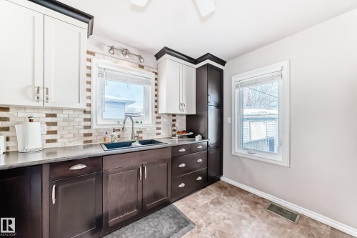 Dual tone kitchen with light countertops, dual tone cabinets, and tasteful backsplash - 3634 113 Avenue, Edmonton, AB - Indoor Photo Showing Kitchen With Double Sink