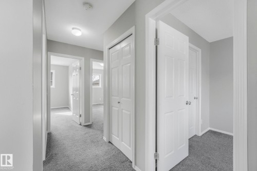 The property features a hallway with carpeted flooring and light grey walls - 123 230 Edwards Drive, Edmonton, AB - Indoor Photo Showing Other Room