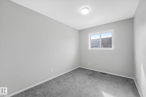 The room features light gray walls, gray carpeting, a single window, and a ceiling-mounted light fixture - 123 230 Edwards Drive, Edmonton, AB - Indoor Photo Showing Other Room