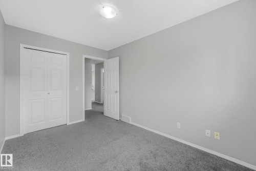 This room features light gray walls, gray carpeting, a ceiling-mounted light fixture, and white bi-fold closet doors - 123 230 Edwards Drive, Edmonton, AB - Indoor Photo Showing Other Room