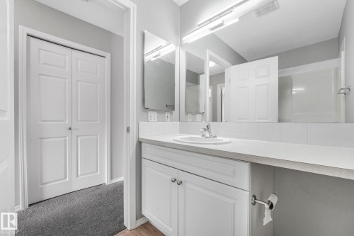 Bathroom featuring a white vanity with panelled cabinet doors, a drop-in sink, and a large mirror - 123 230 Edwards Drive, Edmonton, AB - Indoor Photo Showing Bathroom