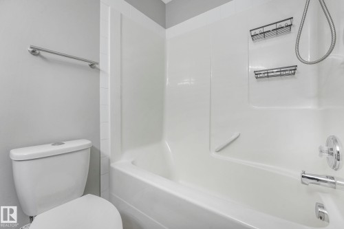 Bathroom featuring a white toilet, a white shower and bath unit, and a chrome towel bar - 123 230 Edwards Drive, Edmonton, AB - Indoor Photo Showing Bathroom