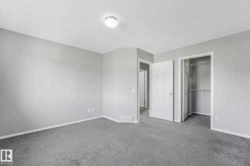 The room features light gray walls, gray carpeting, a flush mount ceiling light fixture, and a built-in closet with shelving - 123 230 Edwards Drive, Edmonton, AB - Indoor Photo Showing Other Room
