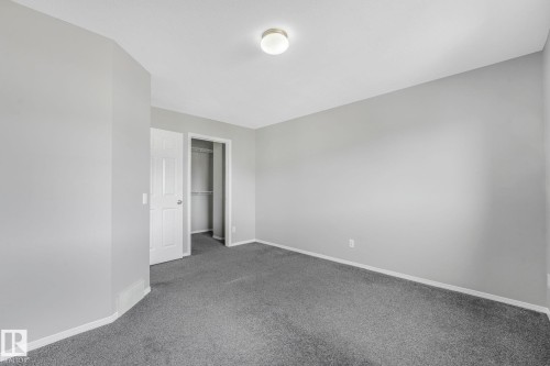 This room features light gray painted walls, dark gray carpeting, and white baseboards - 123 230 Edwards Drive, Edmonton, AB - Indoor Photo Showing Other Room