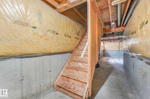 The property features an unfinished basement with a concrete floor and exposed wooden ceiling beams - 123 230 Edwards Drive, Edmonton, AB - Indoor