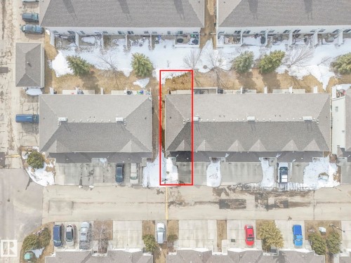 Aerial view highlighting the property's roofline, surrounding paved areas, and green spaces with scattered trees - 123 230 Edwards Drive, Edmonton, AB - Other