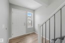 Entrance area featuring wood-look flooring, a white paneled door, and a staircase with a white railing and dark balusters - 123 230 Edwards Drive, Edmonton, AB  - Indoor Photo Showing Other Room 