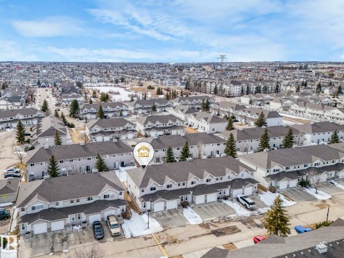 Aerial view of the property and surrounding residential neighborhood, featuring rows of townhomes with attached garages and paved driveways - 123 230 Edwards Drive, Edmonton, AB - Outdoor With View