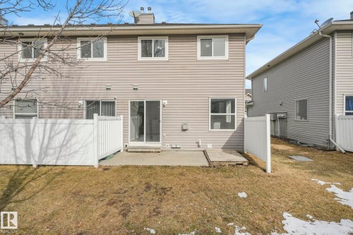 The property features a concrete patio and a fenced yard with a partially visible tree - 123 230 Edwards Drive, Edmonton, AB - Outdoor With Exterior
