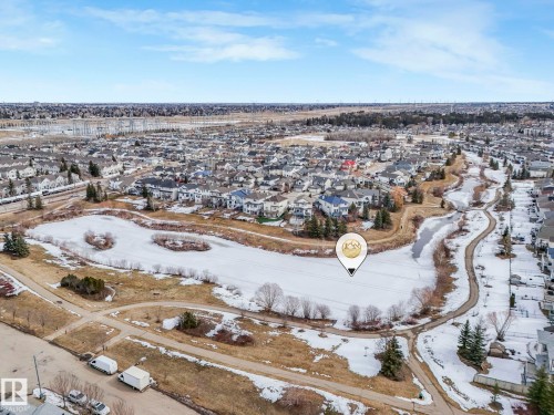 Aerial view showcasing the surrounding neighborhood, featuring residential properties, a frozen pond, and walking paths - 123 230 Edwards Drive, Edmonton, AB - Outdoor With View