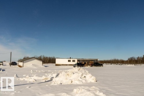 The property includes a white residential building and an additional white structure, set within a vast open area covered in snow - 112, 57004 Range Rd 105, Rural St. Paul County, AB - Outdoor