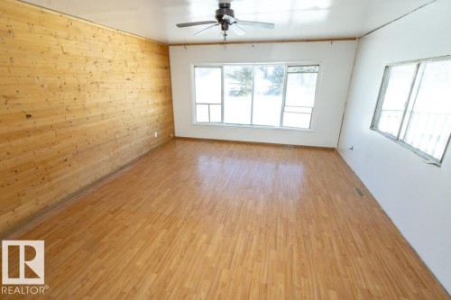 This inviting room features warm wood paneling on one wall, complemented by light-colored flooring throughout - 112, 57004 Range Rd 105, Rural St. Paul County, AB - Indoor Photo Showing Other Room