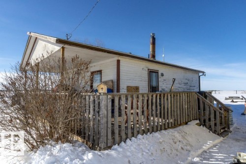 The property features a white exterior with a covered porch and a wooden deck - 112, 57004 Range Rd 105, Rural St. Paul County, AB - Outdoor