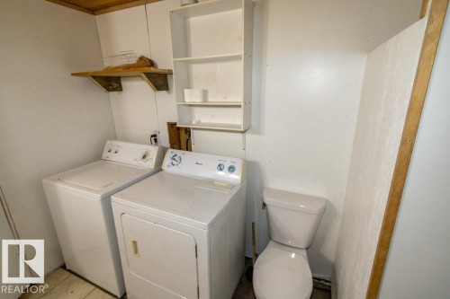Utility space featuring a washing machine, a dryer, a toilet, and wall-mounted shelving - 112, 57004 Range Rd 105, Rural St. Paul County, AB - Indoor Photo Showing Laundry Room