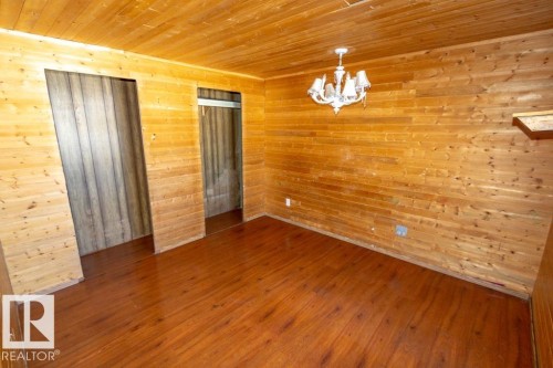 This room features extensive wood paneling on the walls and ceiling, complemented by wood flooring - 112, 57004 Range Rd 105, Rural St. Paul County, AB - Indoor Photo Showing Other Room
