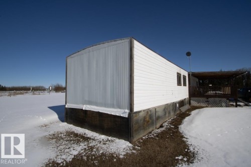 The property features white siding and a covered deck, surrounded by a snow-covered yard - 112, 57004 Range Rd 105, Rural St. Paul County, AB - Outdoor With Exterior