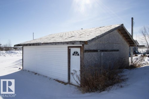 The property features an outbuilding with a pitched roof, a white door, and a combination of white siding and paneling - 112, 57004 Range Rd 105, Rural St. Paul County, AB - Outdoor