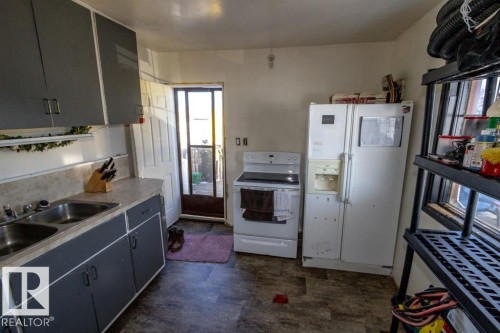 The kitchen features dark grey cabinetry, a double basin stainless steel sink, a white refrigerator, and a white electric range - 112, 57004 Range Rd 105, Rural St. Paul County, AB - Indoor Photo Showing Kitchen With Double Sink
