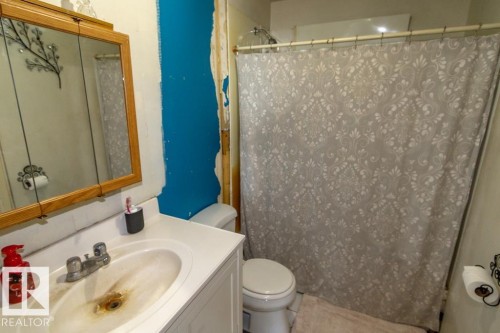 Bathroom featuring a vanity with an integrated sink, a toilet, and a shower area with a patterned shower curtain - 112, 57004 Range Rd 105, Rural St. Paul County, AB - Indoor Photo Showing Bathroom