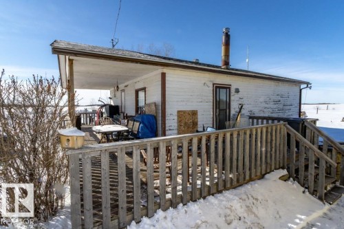 The property features a wood deck with a railing and an overhang, accessible via wooden stairs - 112, 57004 Range Rd 105, Rural St. Paul County, AB - Outdoor