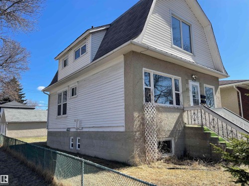 The property features a Gambrel style roof, white siding, and a stucco finish on the lower level - 11161 96 Street, Edmonton, AB - Outdoor With Exterior