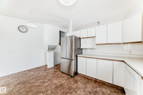 The kitchen features white cabinetry, white countertops, and a stainless steel refrigerator - 1832 42 Street, Edmonton, AB - Indoor Photo Showing Kitchen