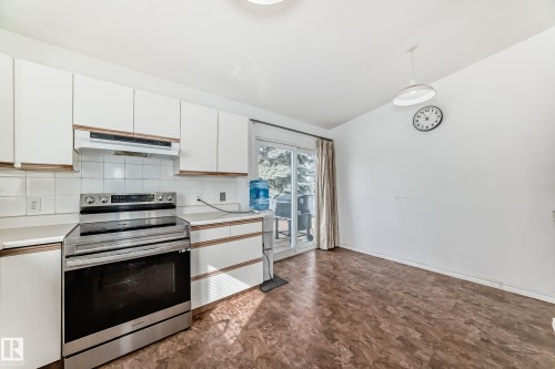 Kitchen with white cabinetry, a white tiled backsplash, and stainless steel oven and range hood - 1832 42 Street, Edmonton, AB - Indoor Photo Showing Kitchen
