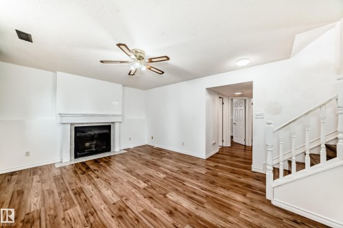 Living area featuring hardwood floors, a fireplace with a white mantel, and a ceiling fan - 1832 42 Street, Edmonton, AB - Indoor With Fireplace